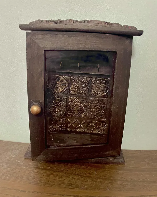Small dark wooden key cupboard with a patterned glass door