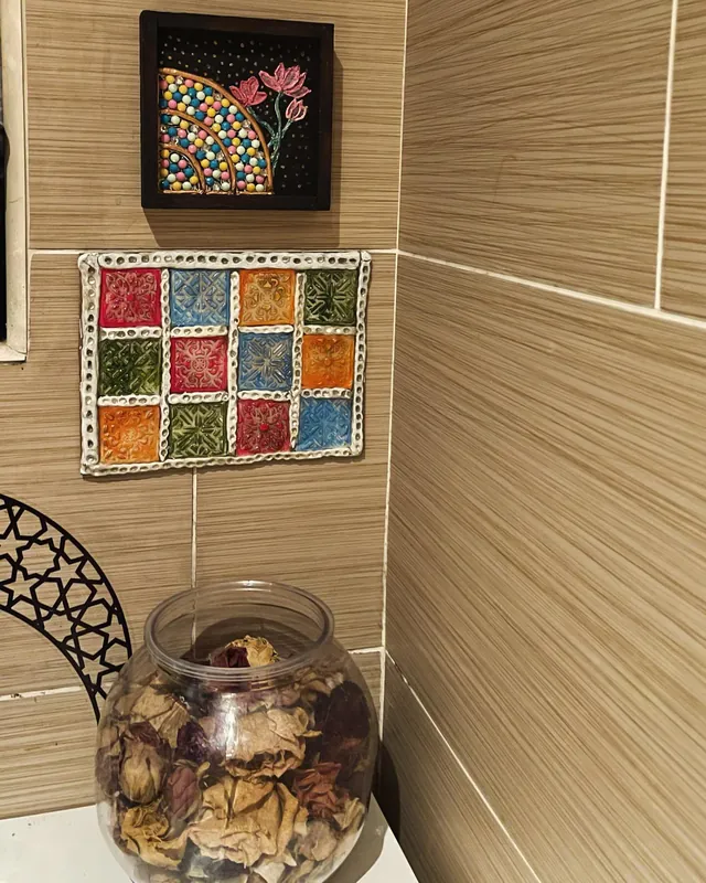 Framed clay tile artworks hanging on a tiled wall